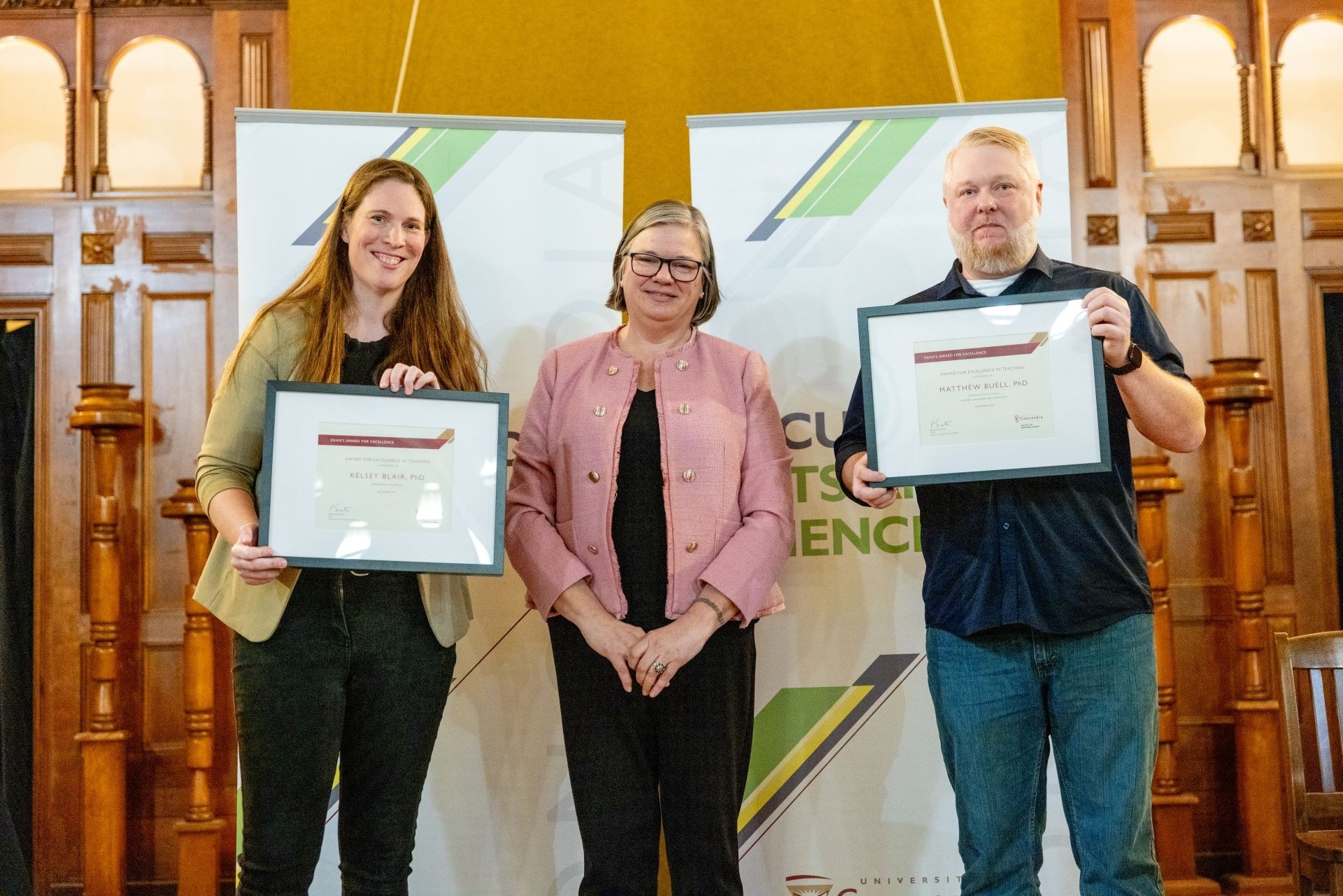 Two young teachers, a woman and a man, standing on each side of Dean Sicotte holding their framed award