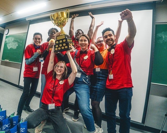 The 7-people team wearing red t-shirts and holding their trophee