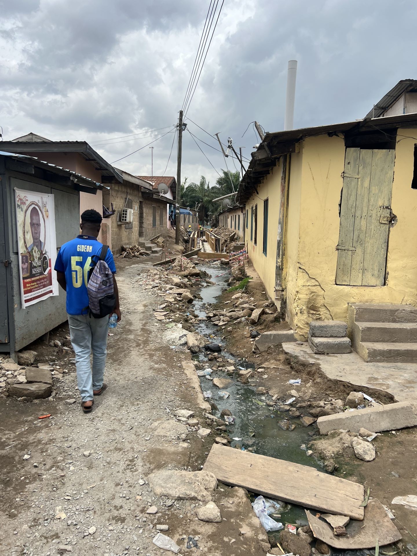 Gideon Azunre (Department of Geography, Planning & Environment) is carefully navigating Alogboshie, a migrant community nestled between high-class settlements and rigid highway infrastructures. The image shows an apparent lack of critical amenities such as drains and walkable paths.