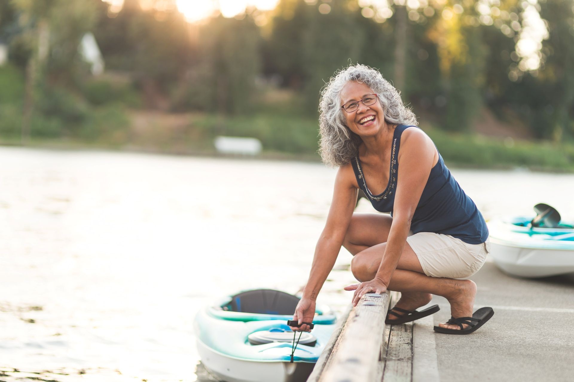 A smiling woman prepares to get into a kayak