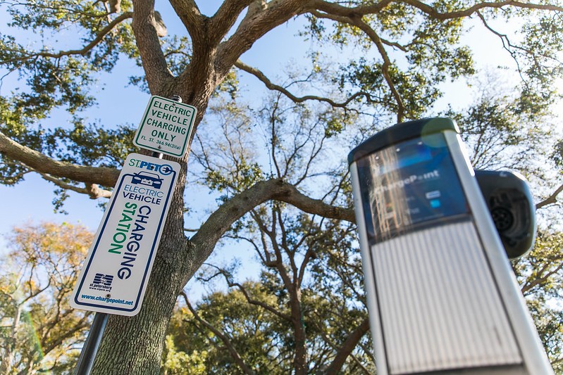 An electric vehicle charging station with an identifying sign to its left 