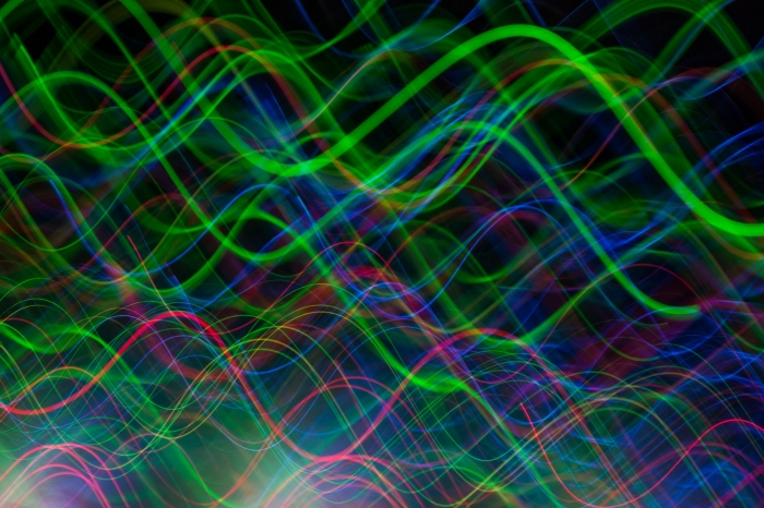 A mass of green, blue and pink sine waves moving across a dark background
