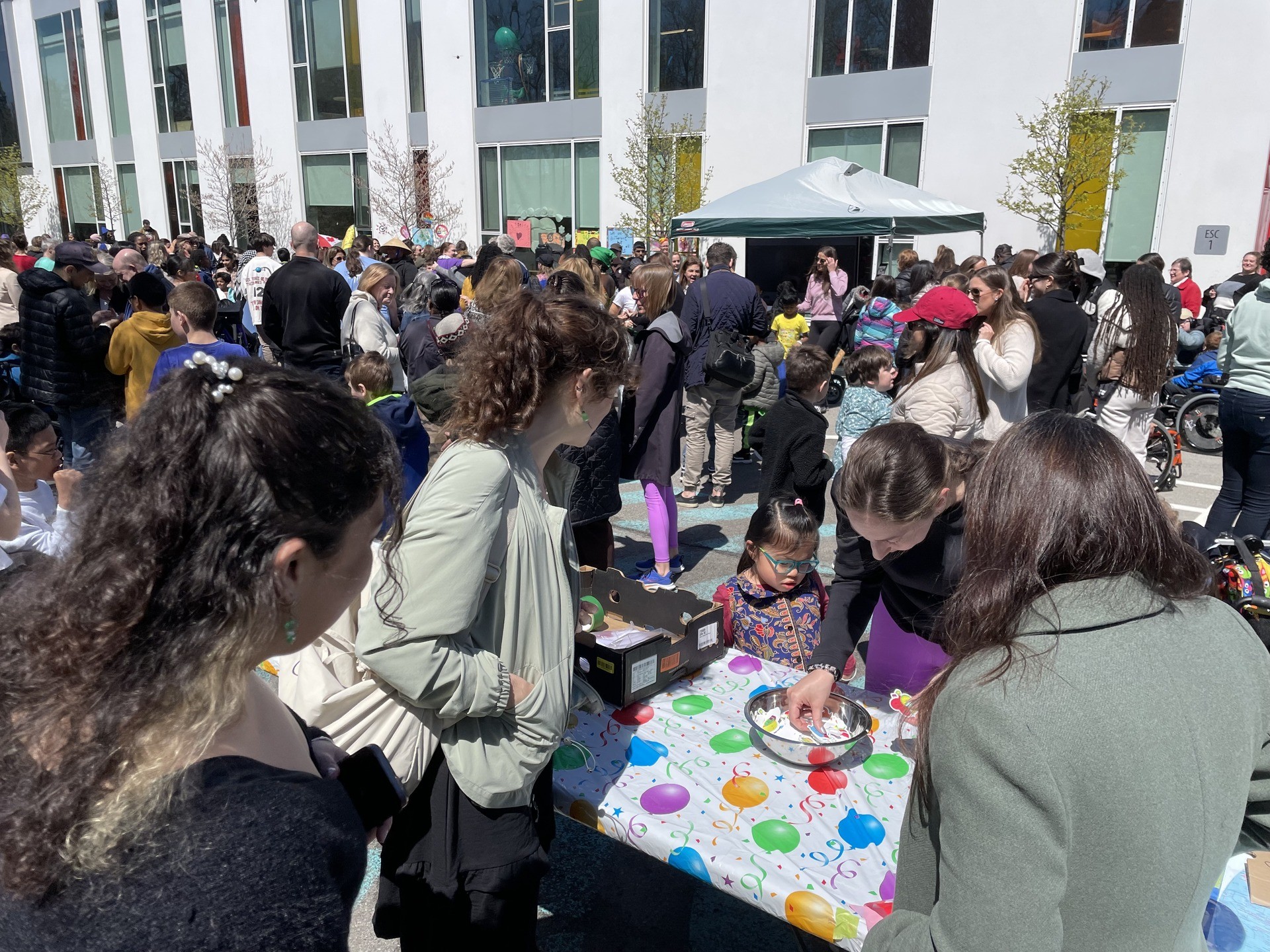 A group of people stand around signing a card in the street.