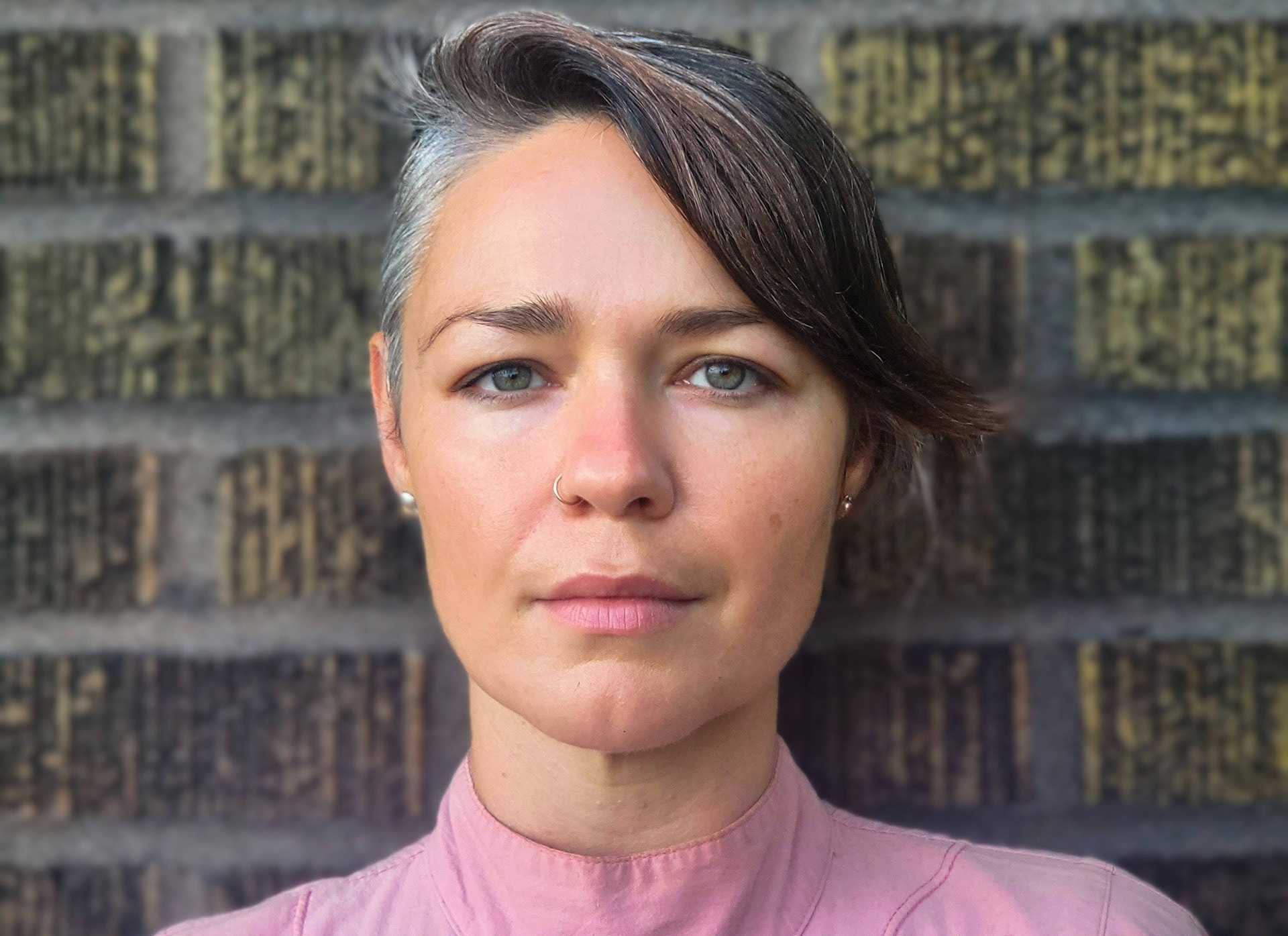 Picture of woman with pink shirt in front of brick wall