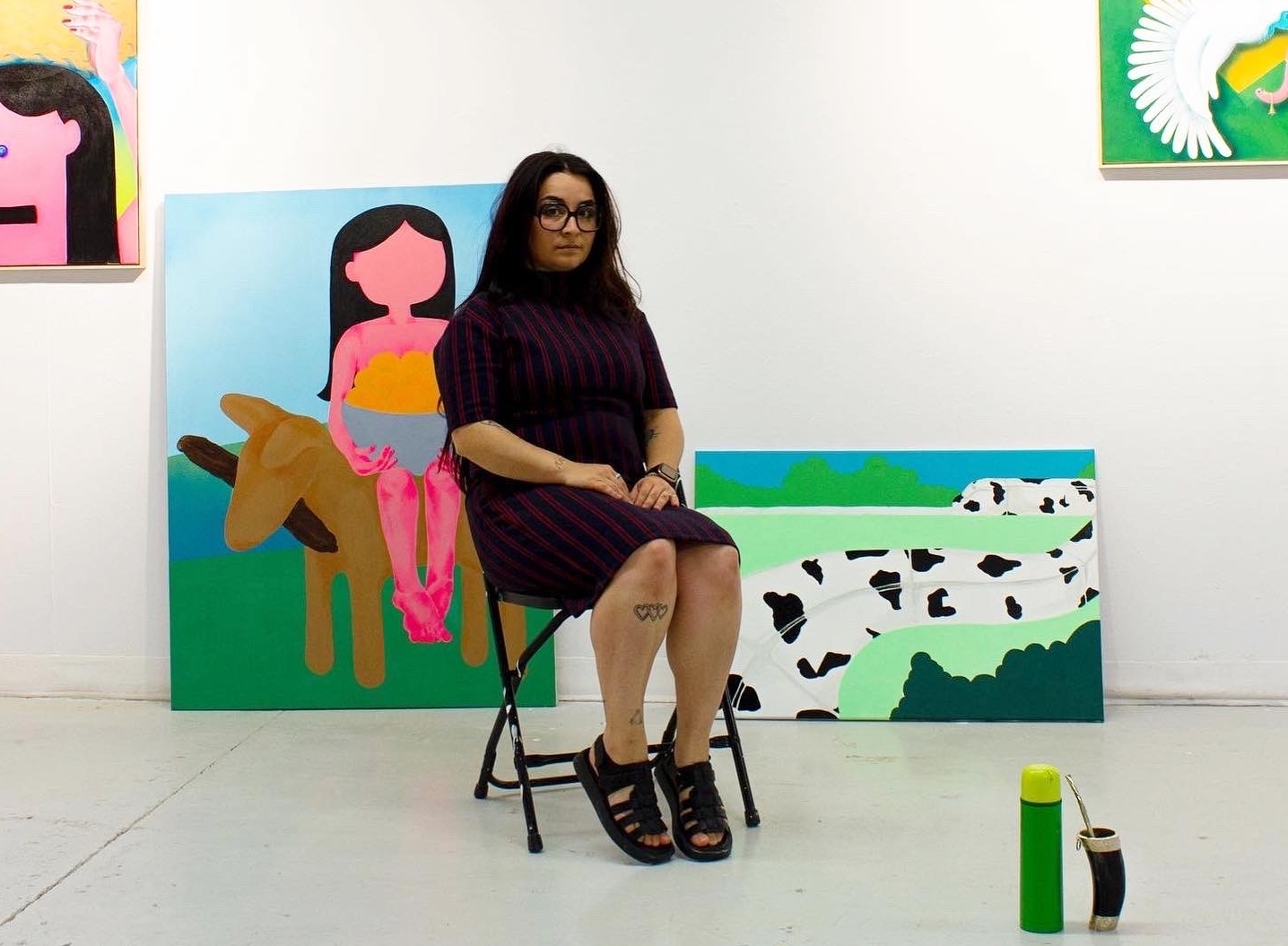 Woman sitting in room with colorful paintings in the back
