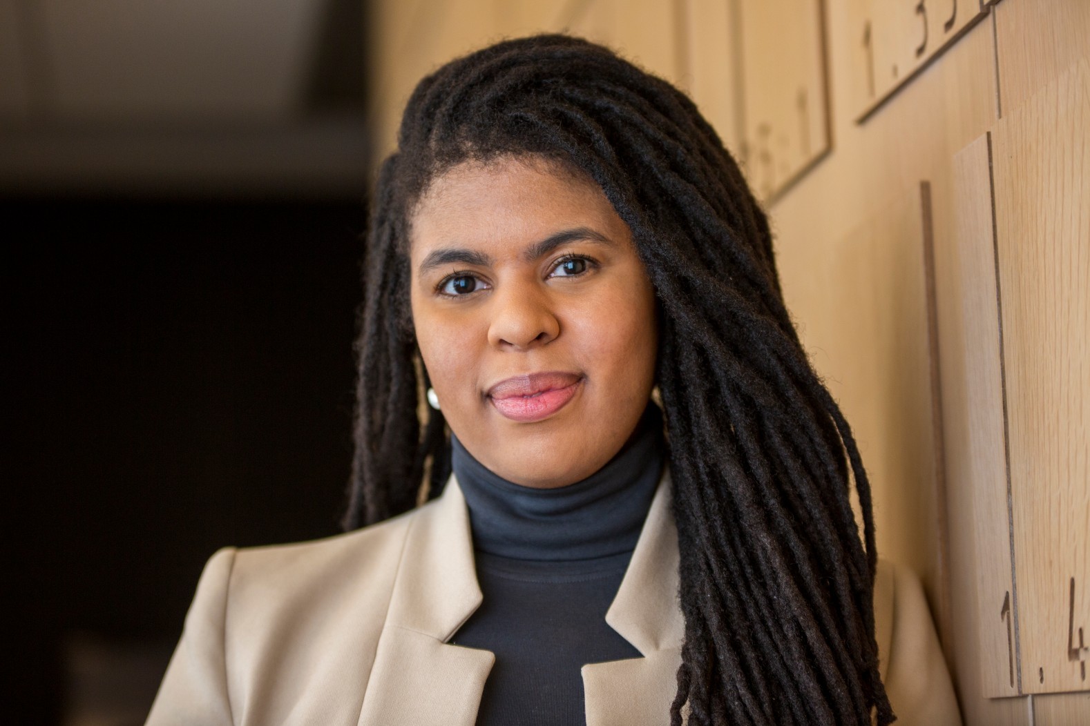 Joana Joachim Portrait of professional Black woman with long hair against wood wall