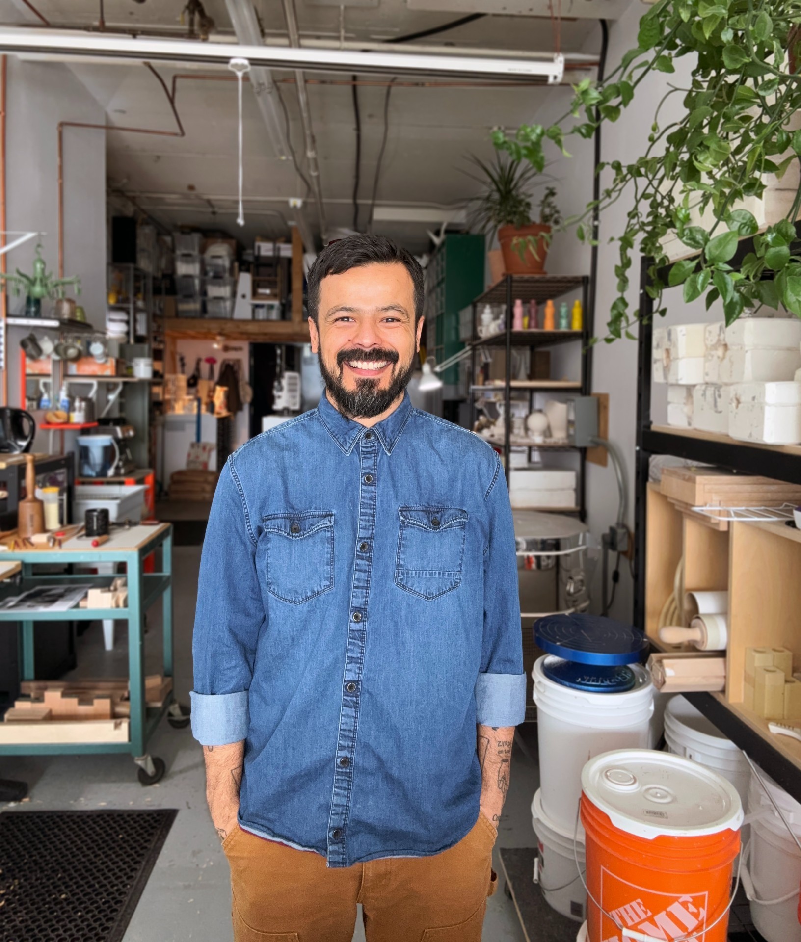 Juan Ortiz Apuy Man in art studio with large recipients and hanging plants