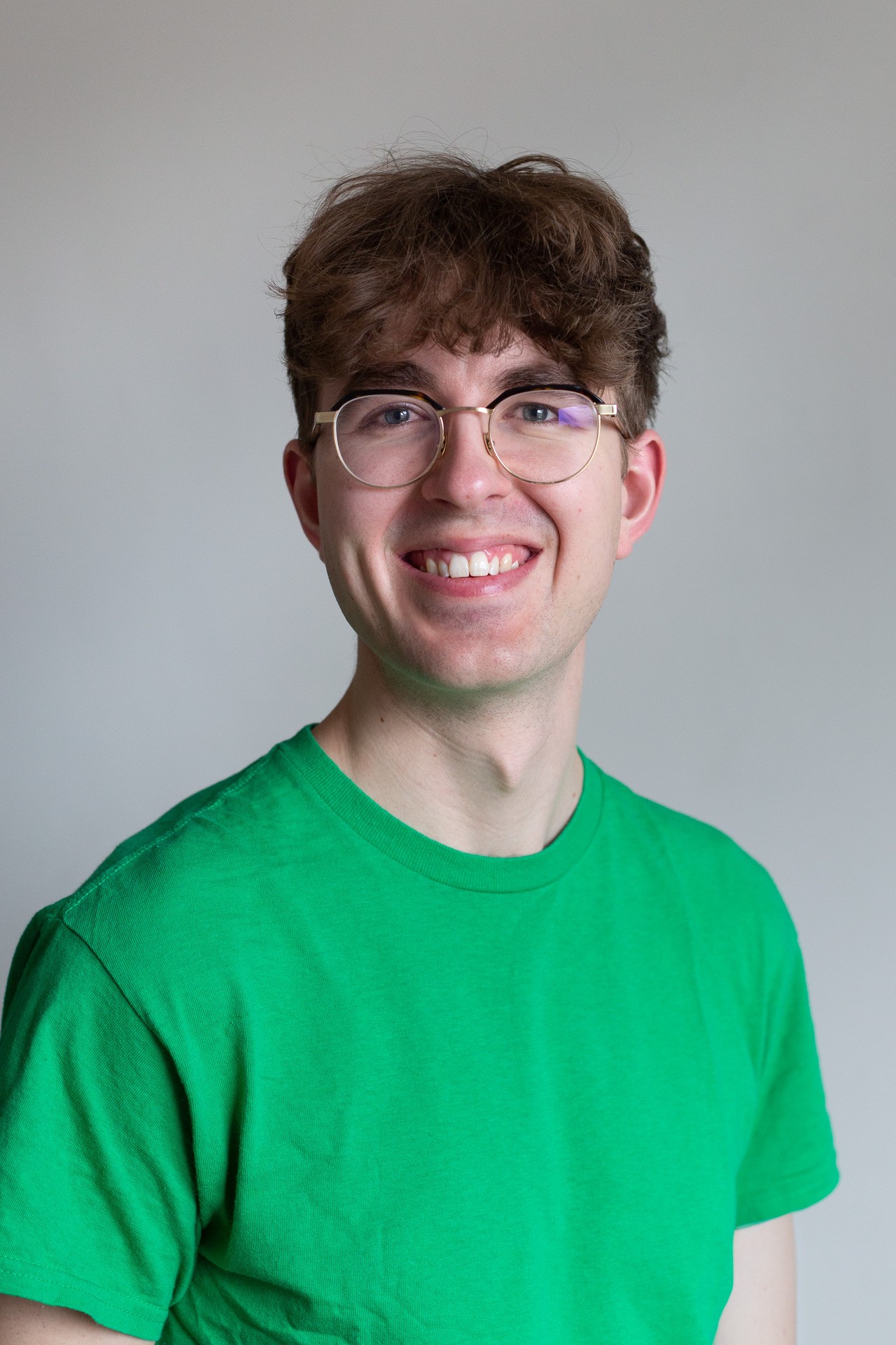 Young man with glasses smiling, wearing green shirt