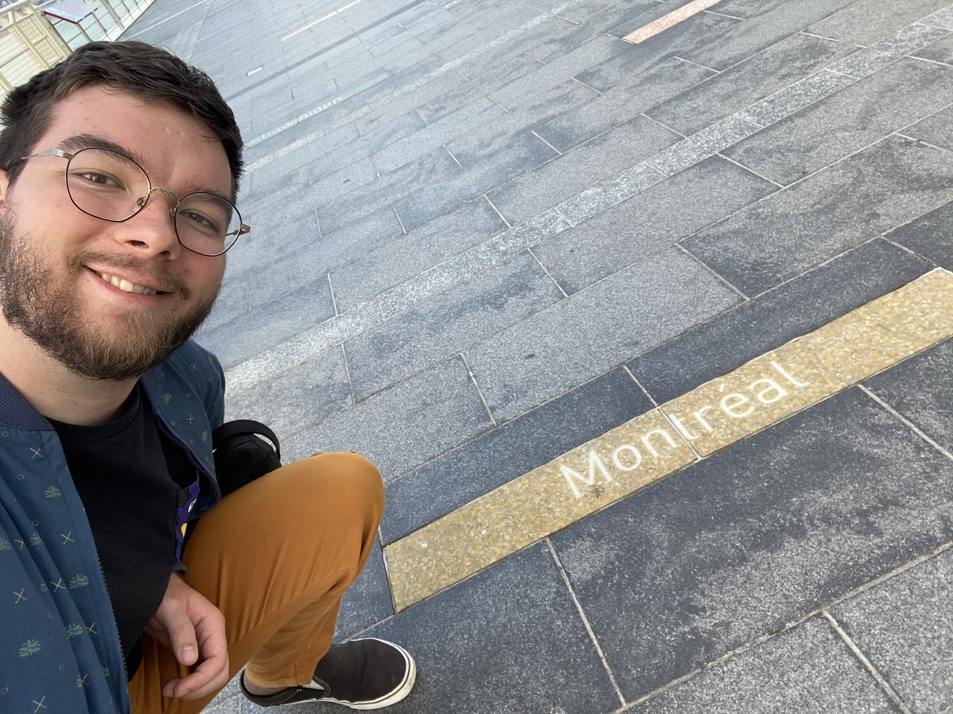 Young man showing Montreal sign on sidewalk 