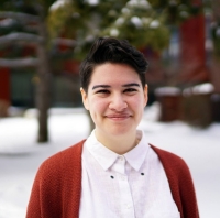 Smiling person with white buttoned shirt and red cardigan