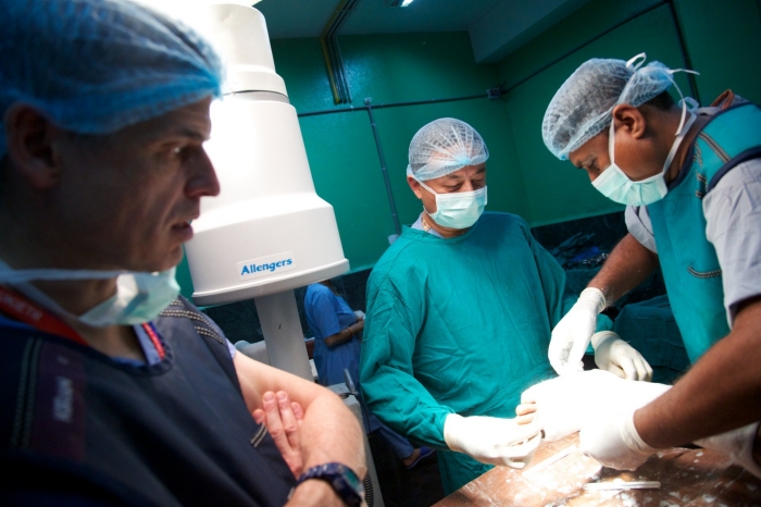 Dr Colin Walker, a consultant orthopaedic surgeon from Glasgow, part of the UK's Emergency Medical Team responding to the Nepal earthquake Three surgeons in an operating room conduct surgery on a patient