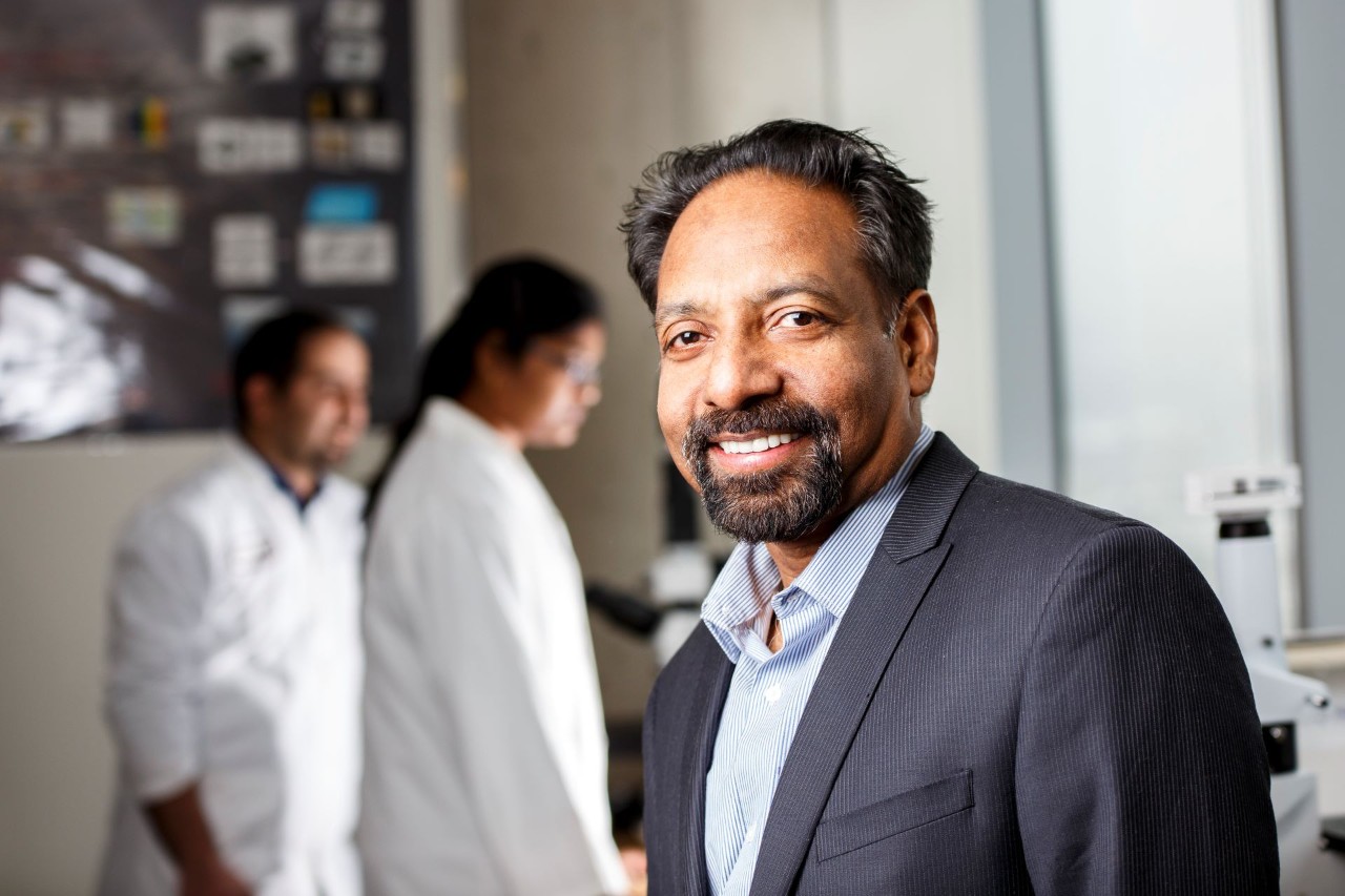 A man in a blue shirt and dark blue jacket in a lab