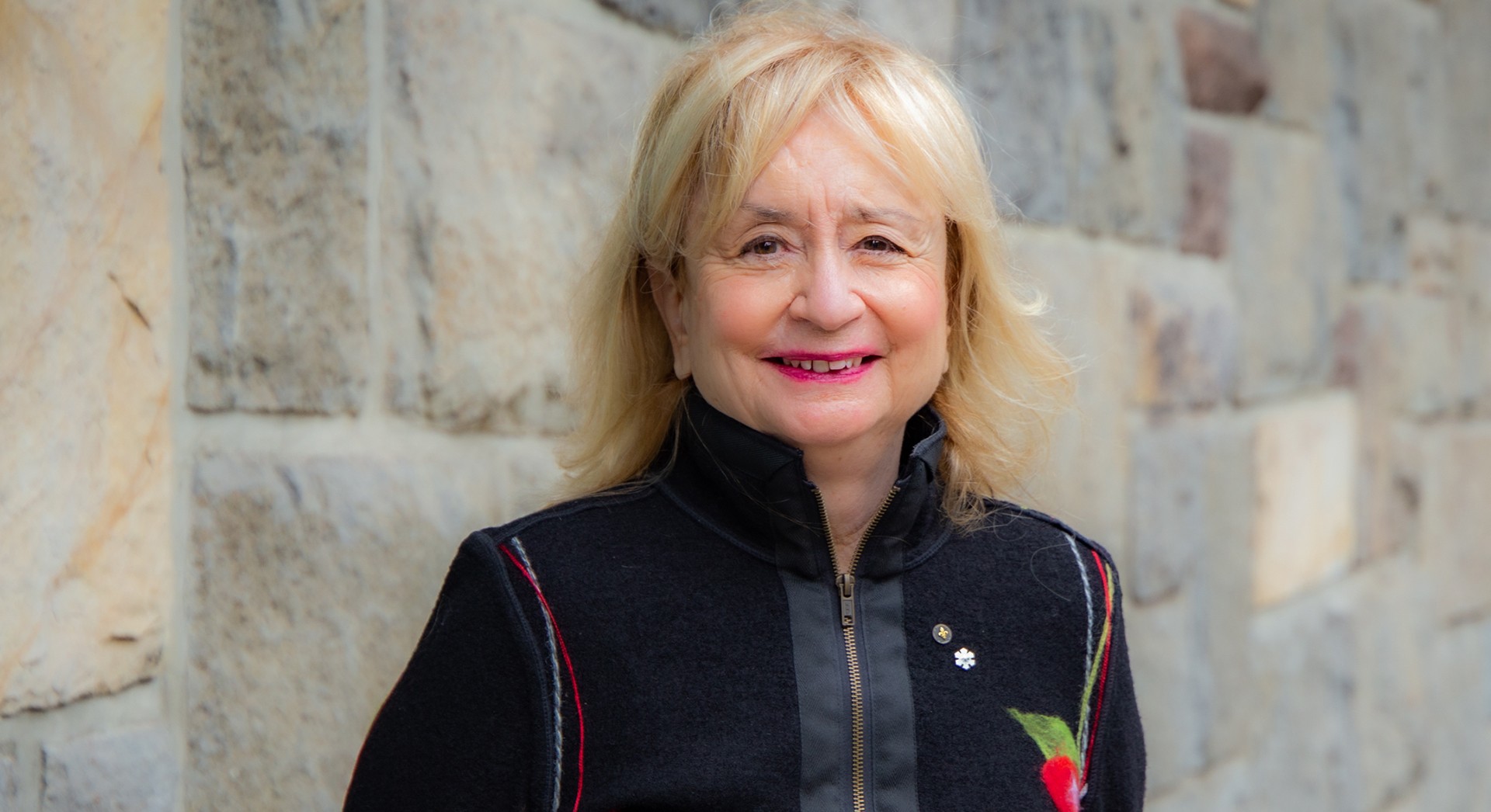 Louise Champoux-Paillé smiling. She has blonde hair and is wearing red lipstick.