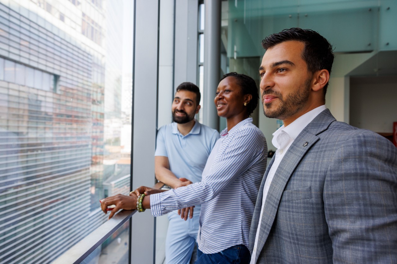 Three students look out window of MB building