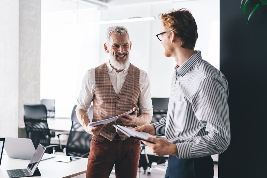 Two male colleagues smile at each other