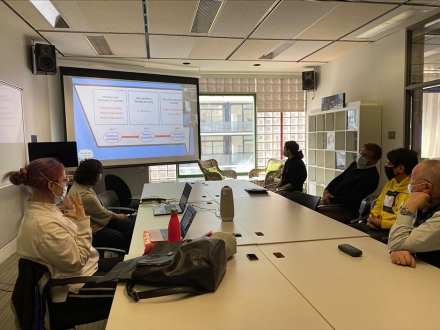 Photo of the workshop attendees around a table and in front of a large screen