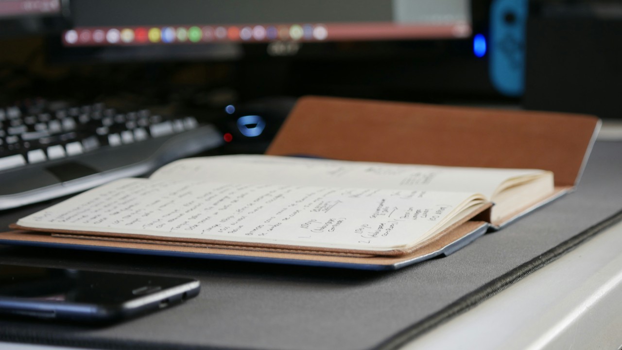 Desk with open notebook, laptop, smartphone