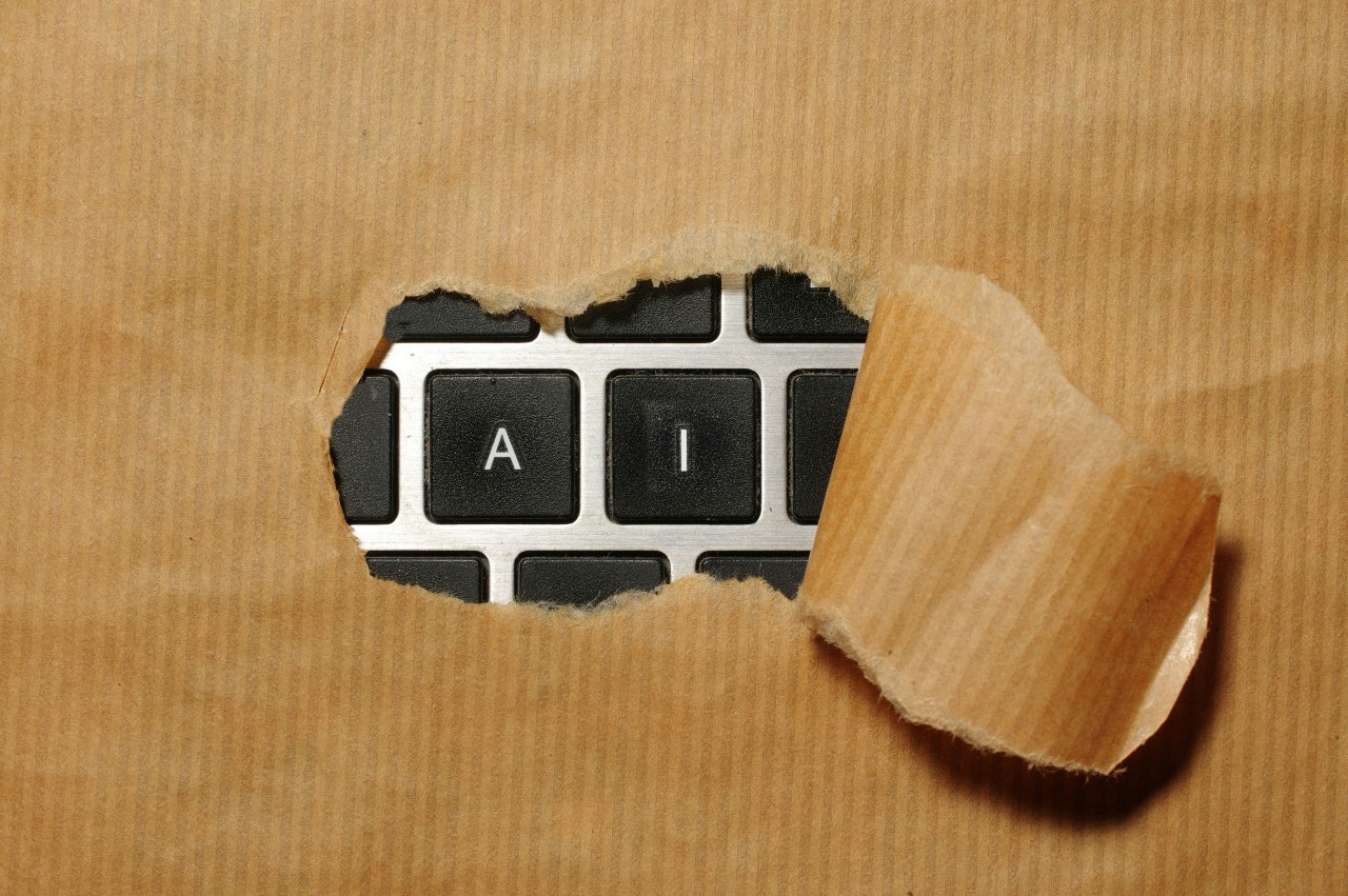 Brown paper over a keyboard torn to reveal the letters A and I