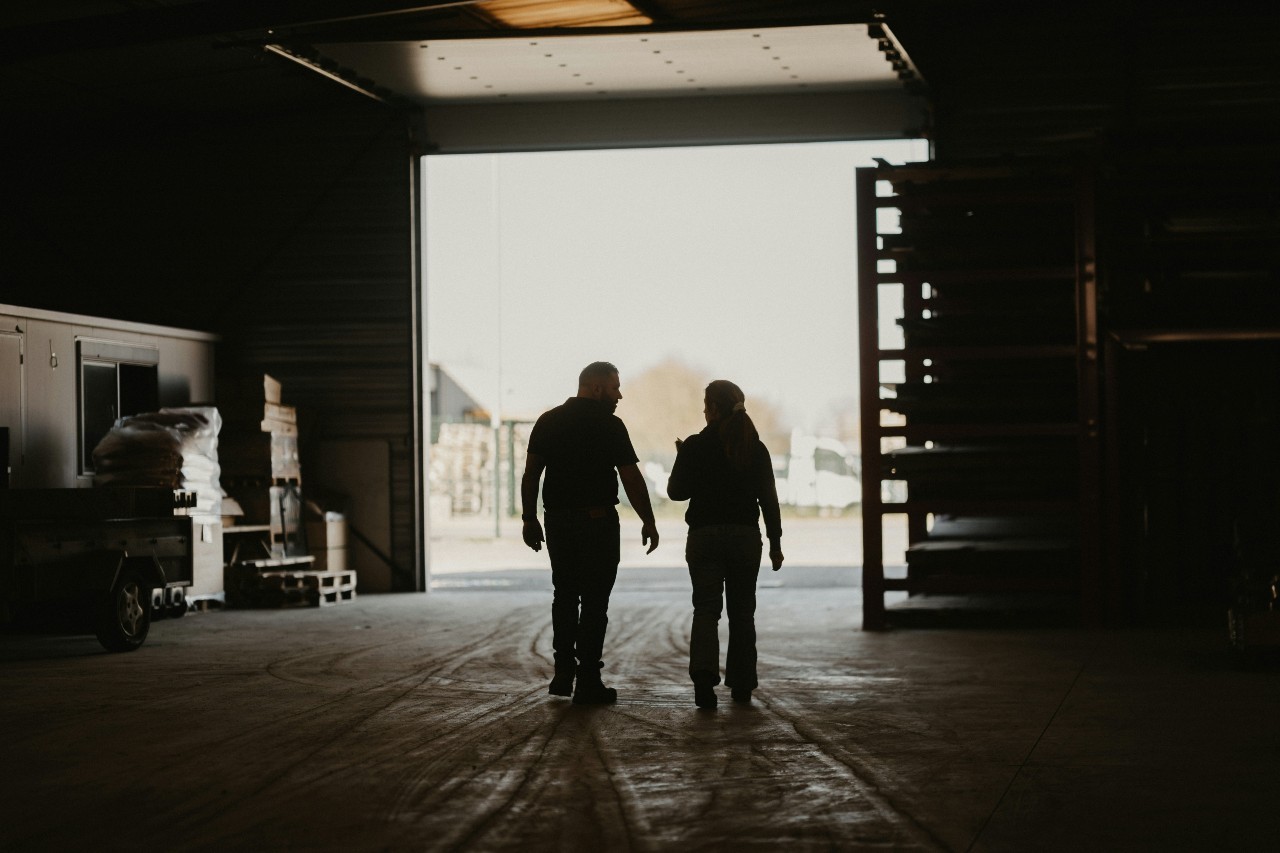Silhouette of man and woman walking and talking to each other in a warehouse