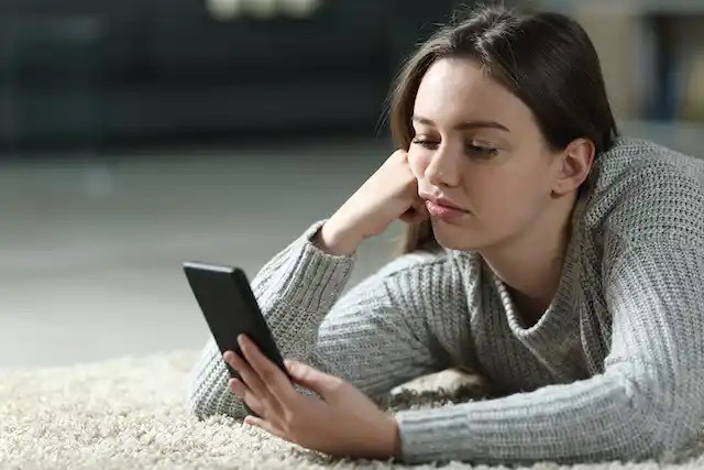 Shutterstock image young woman looking disinterestedly at her phone