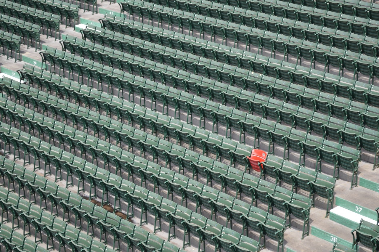 Arena of empty green seats with one red seat