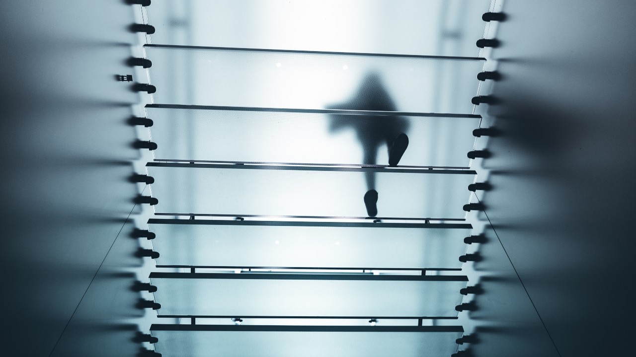 Silhouette of a person walking on a transparent glass floor from below