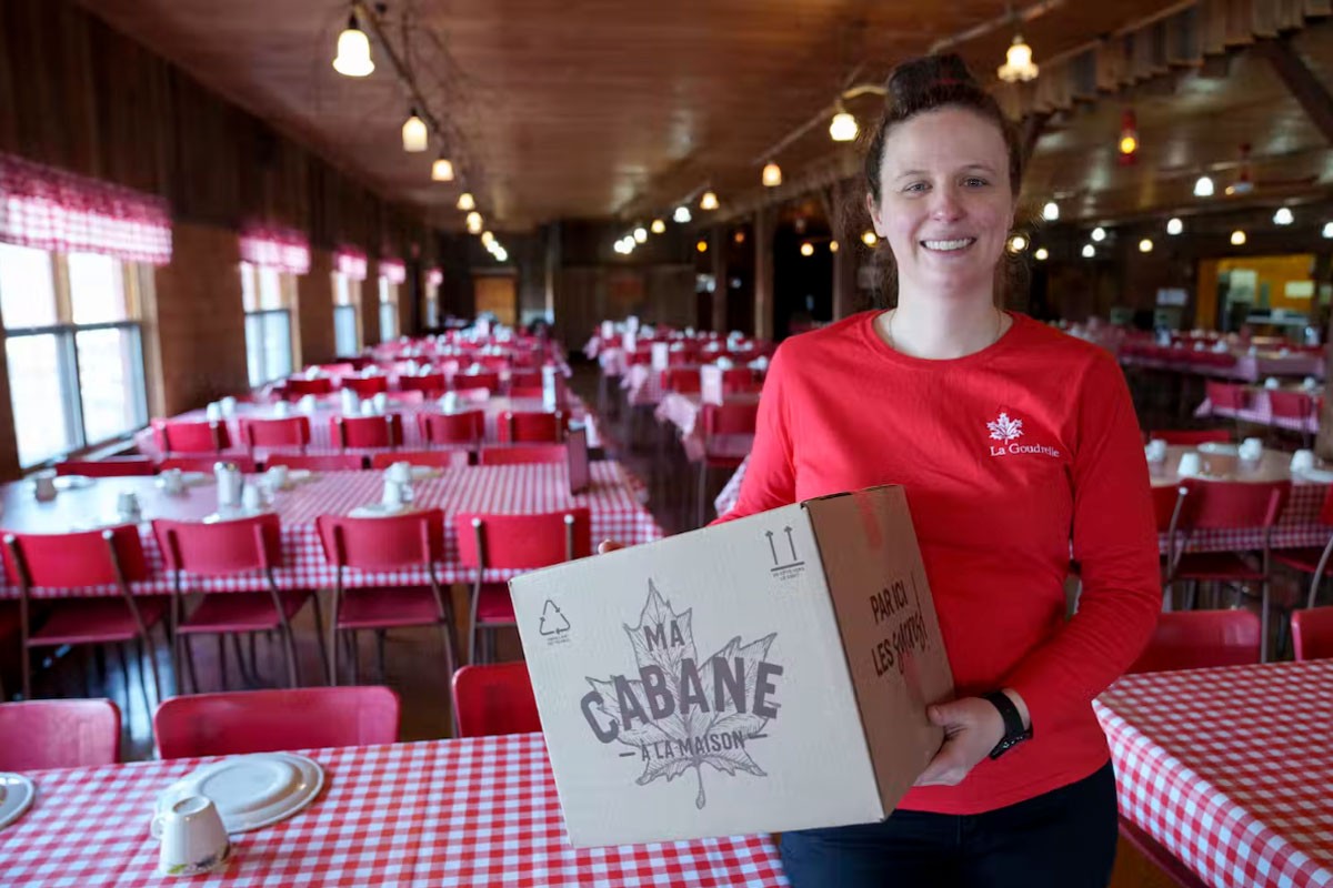 A woman holds a box in a sugar shack setting