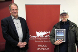 Daniel Houde, Director of the Campus Retail Stores, is pleased to present a new iPad (courtesy of the Campus Retail Stores) to raffle winner Vince MacDougall of Mail Services. | Photo by Kim Barbier, Concordia University