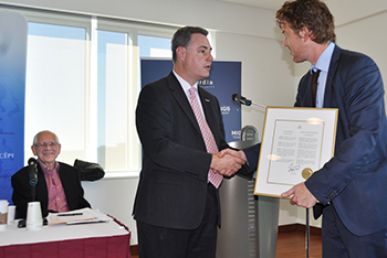  Ottawa City Councillor Mark Taylor presents his city's designation of Will to Intervene (W2I) Day to Kyle Matthews, senior deputy director of The W2I Project at the Montreal Institute of Genocide Studies.