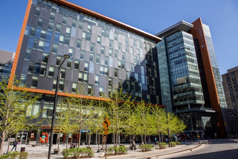 Building with a black exterior and green trees in front.