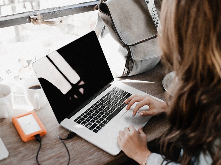 Providing funding for more virtual events is a logical way to support student safety while allowing them to keep up with the latest research developments. | Photo by Andrew Neel on Unsplash A person with long brown hair sitting at a desk with a laptop.