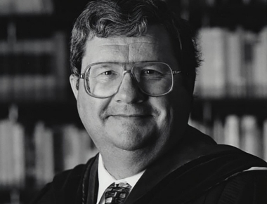 Black and white image of a smiling man wearing glasses