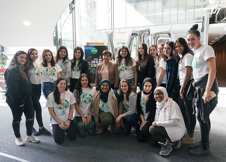 Group of young women gathered together and smiling for the camera in an atrium space.