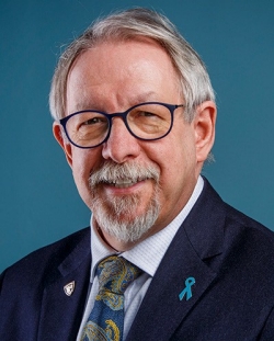 Older smiling gentleman with glasses, a tie and suit.