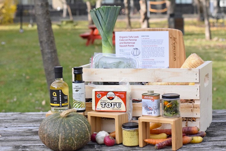 A table in the outdoors with a series of ingredients — pumpkin, olive oil, carrots, tofu — placed on it.