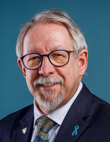 Older gentleman with short grey hair, and grey beard, and glasses.