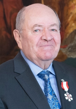 Older smiling gentleman in a grey suit.