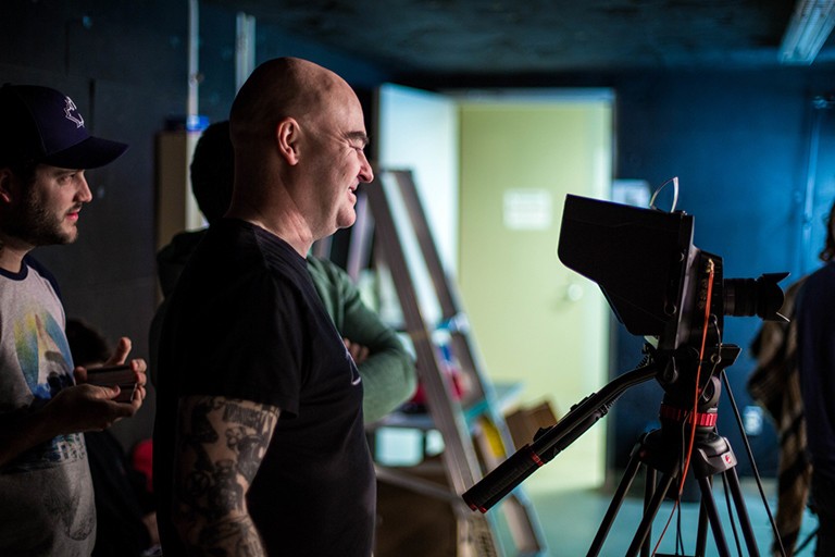 A group of people in a studio setting, looking at the LED display of a film camera.