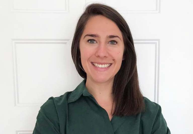 Young, smiling woman with long dark hair and a green shirt.