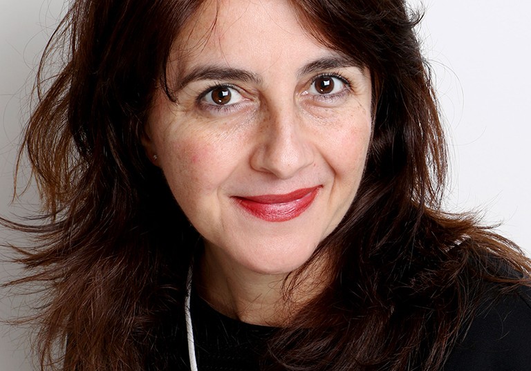 Smiling woman with long, dark brown hair, brown eyes and red lipstick.