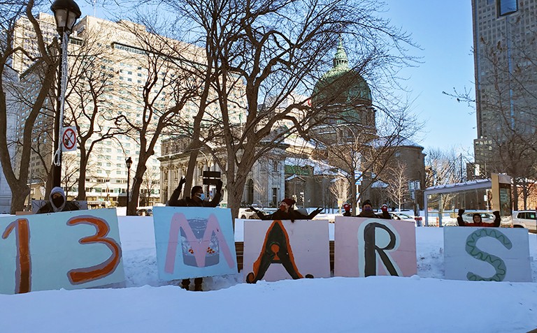 Miracle Montreal Food Drive 5 people wearing masks, distanced, behind posters that collectively read "13 March" in French.
