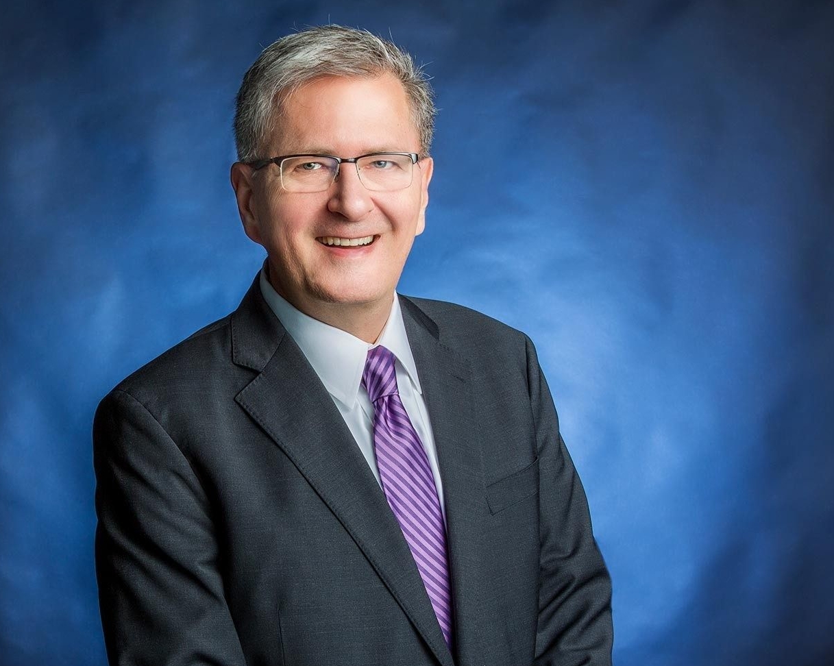 Man wearing charcoal suit and striped purple tie