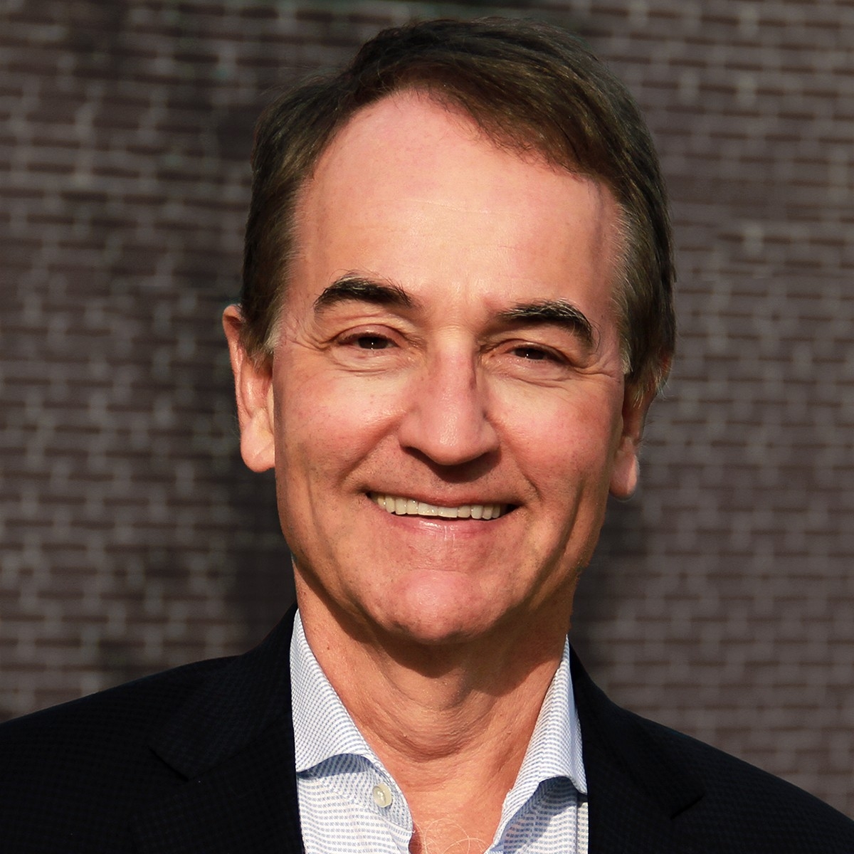 Headshot of smiling man wearing black blacker and light-coloured collared shirt