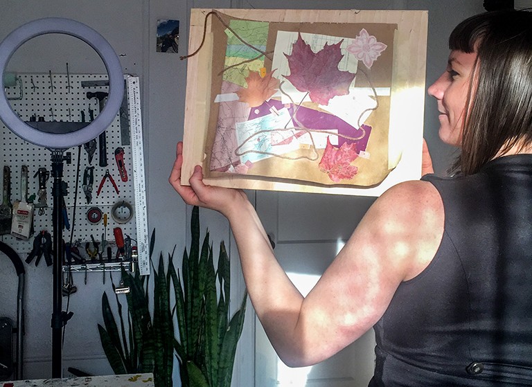 Christine White: “I benefitted from the hands-on activity, since so much of my work is done on a screen these days.” Woman standing with her back to the camera, holding a painting.