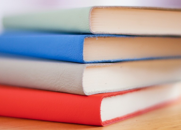 Four leather-bound books on a table top.