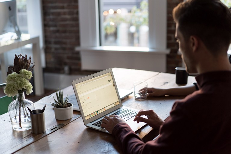 Man using a laptop on a tabletop.