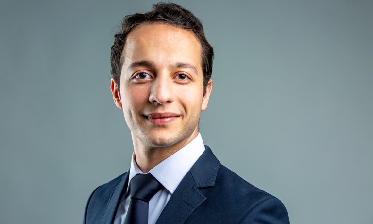 Young man with short, dark hair, a light blue shirt and a navy blue jacket and tie.