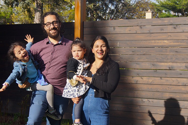 A young smiling family: the father holding his 4 year old and the mother holding a toddler.