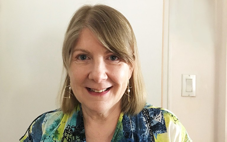 Smiling woman with long, blonde hair and a patterned shirt.