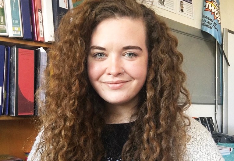 Young, smiling woman with long, curly brown hair.